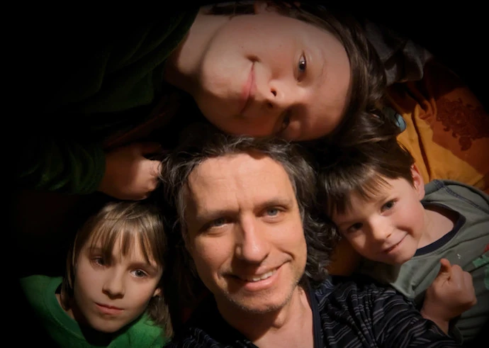 Foto eines Mannes mit 3 Kindern, die auf dem Boden liegen und lächeln
