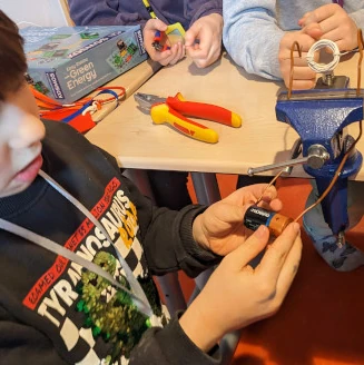 Junge hält eine Batterie, die eine Spule über Magneten zum Drehen bringt